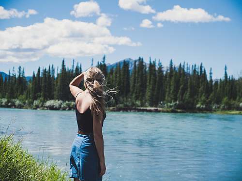 person woman in black camisole standing near river people