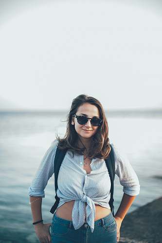 people woman in blue crop-top standing beside body of water person
