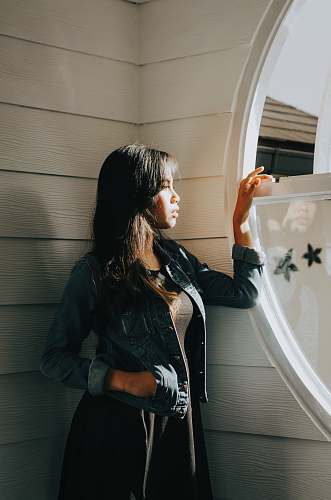 people woman in blue denim jacket standing beside window person