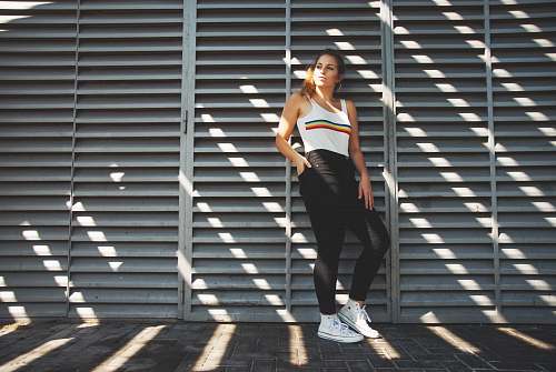 people woman in white tank top leaning on wall person