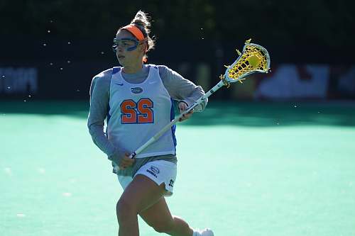 people woman lacrosse player running on field at daytime person
