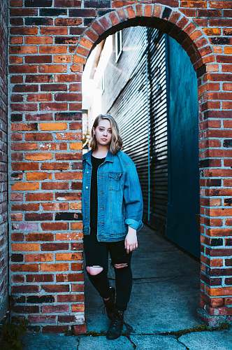 person woman leaning on brown brick wall people