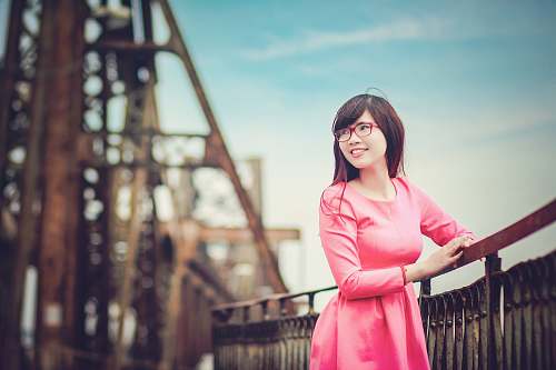 people woman leaning on wooden handrail while facing to her left person