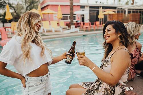 people woman on pool tosing liquor with woman at daytime person