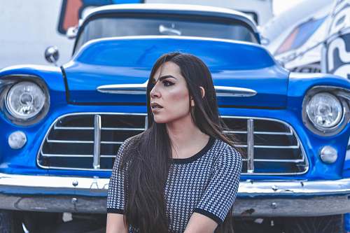 people woman sitting beside blue car person
