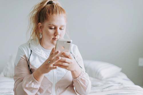 people woman sitting on bed while using gold turned 8 Plus person