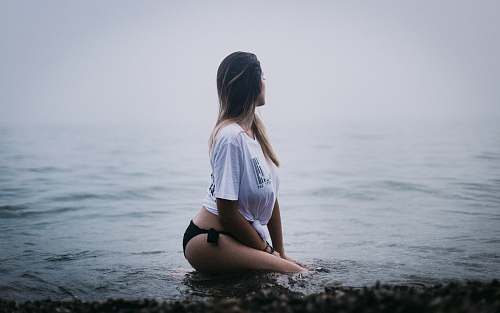 people woman sitting on black surface looking at body of water person
