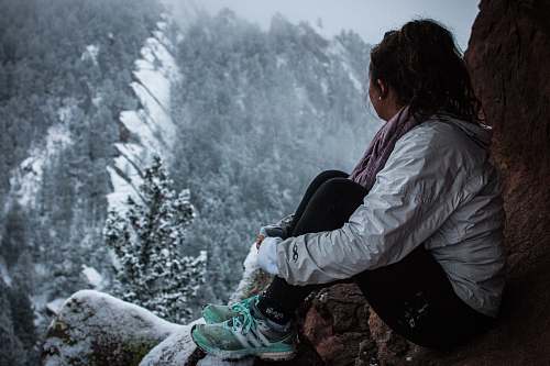 person woman sitting on rock formation under snow people