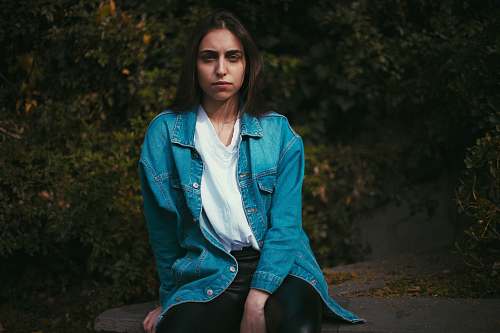 people woman sitting on stone behind trees person
