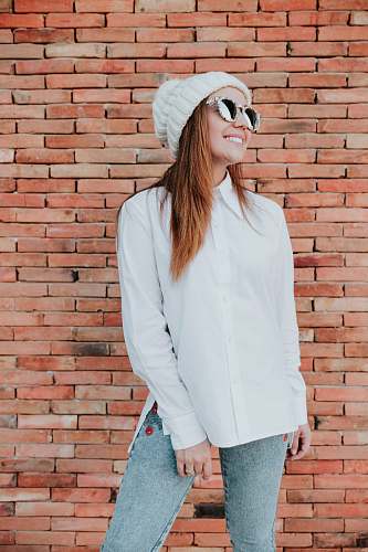 people woman standing at the front of brown brick wall person