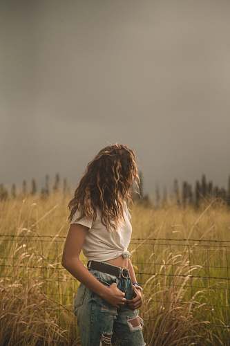 people woman standing beside fence and plants during daytime person