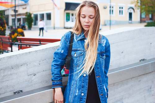 people woman standing beside wall near benches denim