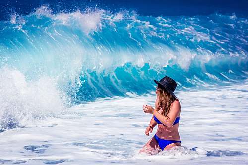 person woman standing in front of water waves bikini