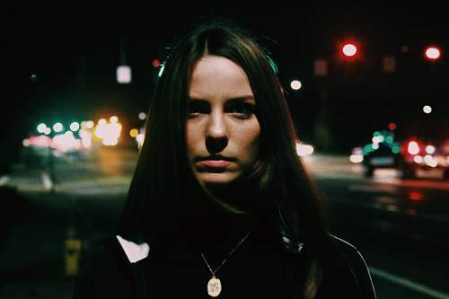 people woman standing near city road during nighttime person