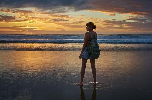 people woman standing near the seashore during golden hour person