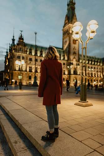 people woman standing near turned on street post and building person