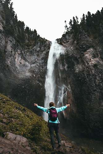 people woman standing on hill facing waterfalls person