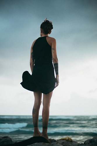 people woman standing on rock looking at the sea during daytime person