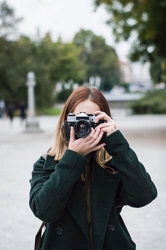 people woman using SLR camera near trees during day person