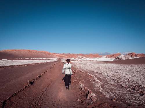 people woman walking along dessert under blue sky during daytime person
