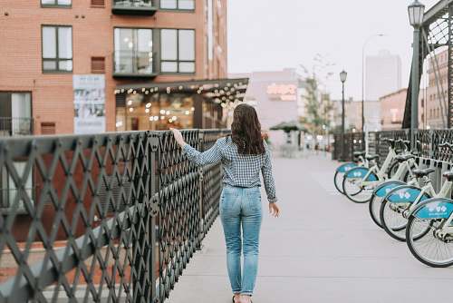 people woman walking outdoors while holding on to black metal railings during day person