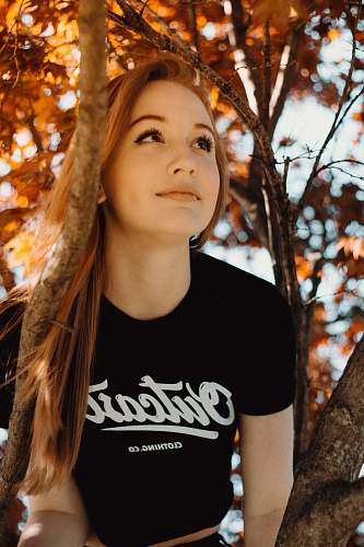 people woman wearing black crew-neck shirt sitting on tree person