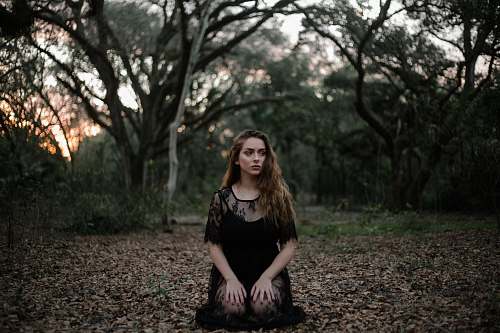 person woman wearing black dress kneeling on ground people