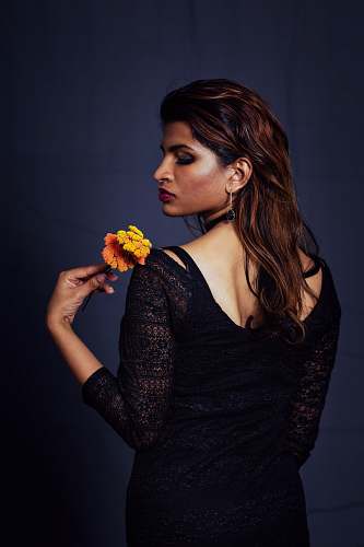 people woman wearing black long-sleeved dress holding flower person