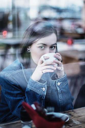 people woman wearing blue denim jacket holding white ceramic teacup person