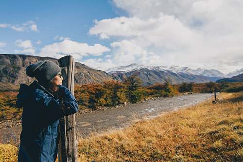 people woman wearing blue jacket leaning on brown wooden post person