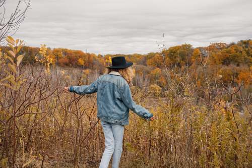 people woman wearing blue jacket walking towards the brown grass person
