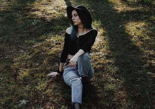 people woman wearing blue jeans sitting on green grass person
