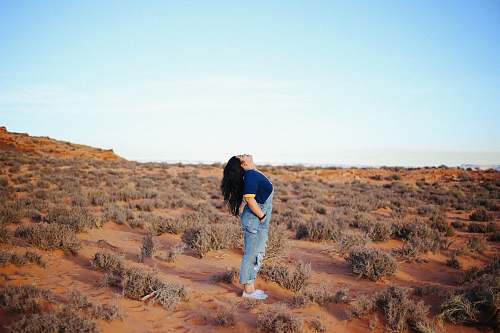people woman wearing denim jumper suit looking up in middle of field person