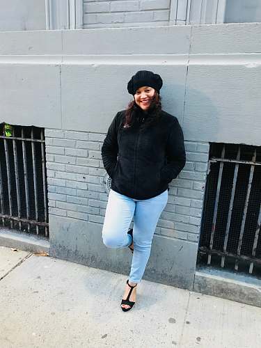 people woman wearing jacket leaning on gray wall person