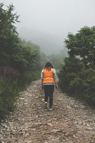 people woman wearing orange life vest walking on pathway during daytime person