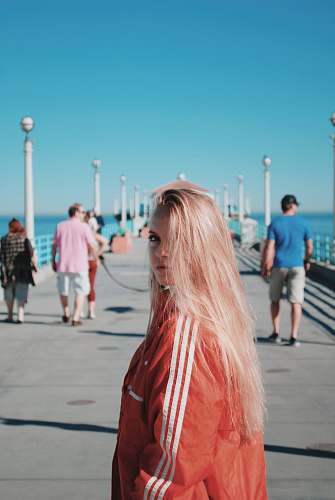 people woman wearing pink windbreaker while walking on dock person