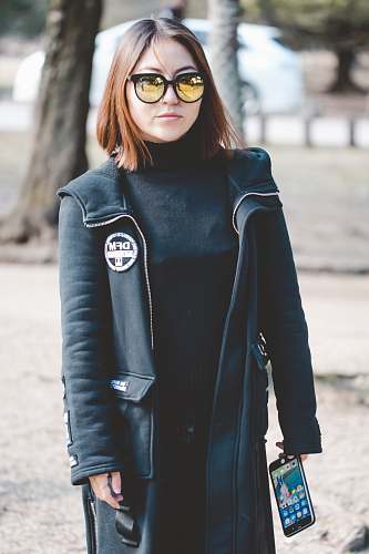 people woman wearing sunglasses holding black Android smartphone person