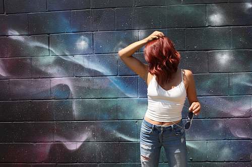 people woman wearing white spaghetti-strap top behind wall person