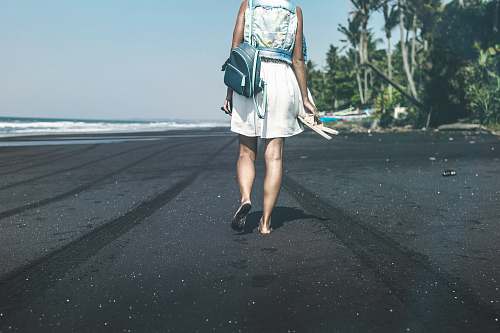 people woman with backpack walking in the beach during daytime person