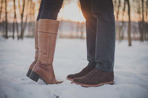 couple two person in brown boots and shoes on snowy forest boots