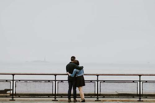 human couple standing in front of fence near body of water person