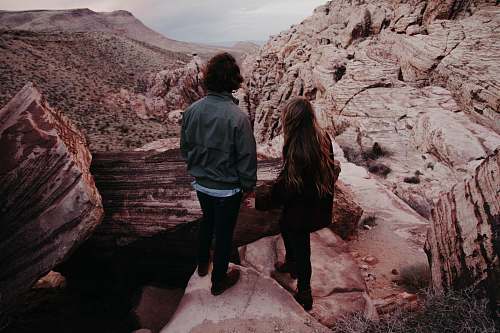 canyon man and woman standing on hill in front of hills during daytime human