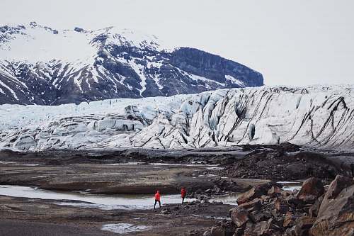 glacier two persons standing near mountain ice