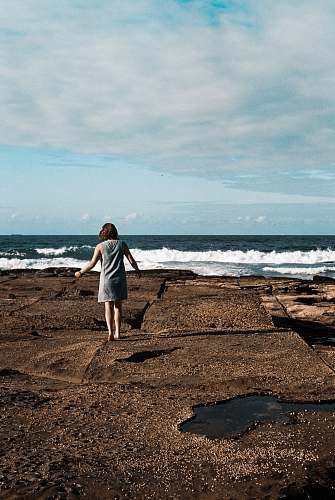 human a woman walking on top of black rock formation person