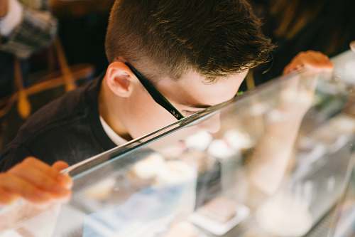 human boy leaning on glass counter person