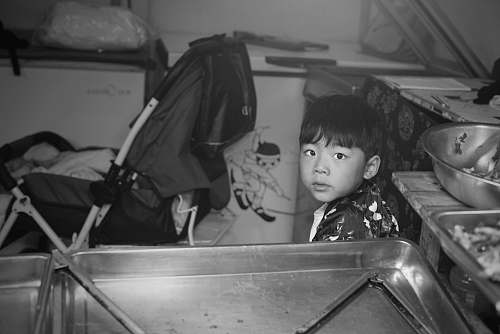 human boy sitting in kitchen black-and-white
