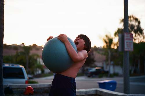 human boy's hugging yoga ball while opening mouth car