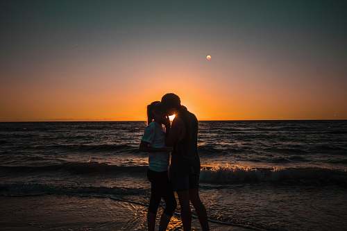 human couple kissing beside seashore person