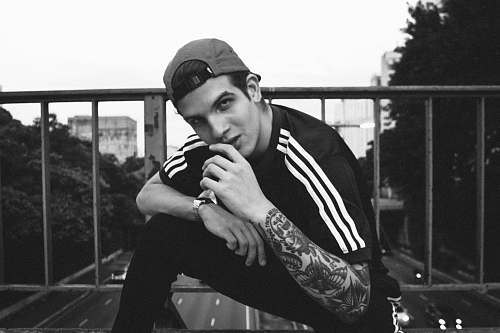 person grayscale photo of man sitting near handrail black-and-white
