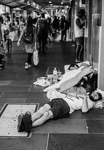 human grayscale photo of man sleeping on street black-and-white